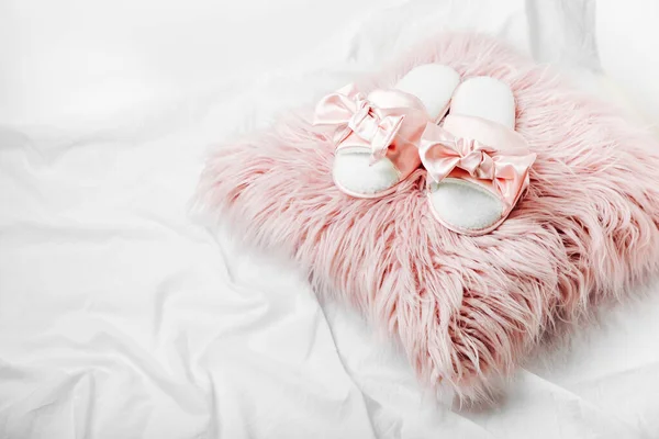 Beautiful female slippers on a pink fur cushion on the bed