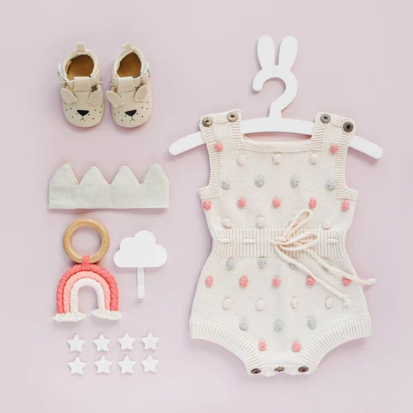 Ensemble De Vetements Et Accessoires Pour Bebe Sur Fond Rose Barboteuse Tricotee A Pois Sur Cintre