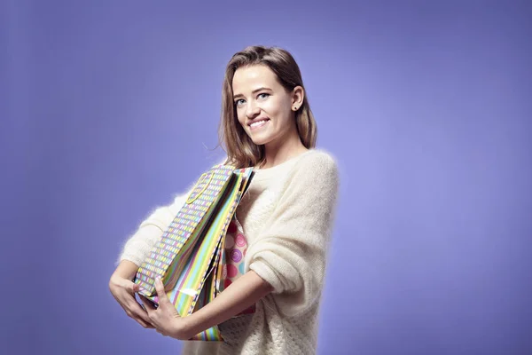 Blonde beautiful caucasian woman happy with present paper bags in hands. Wearing warm sweater, happy emotions. St. Valentines day concept