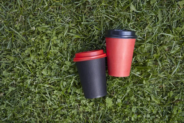 Two paper cups with coffee to take away, red and  black cup on g