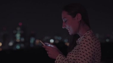 Gece akıllı telefon kullanan Brezilyalı bir kadın.