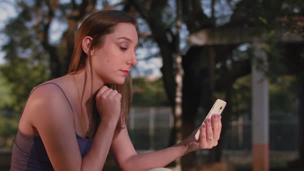 Una mujer brasileña usando smartphone en el atardecer del parque en So Paulo — Vídeo de stock