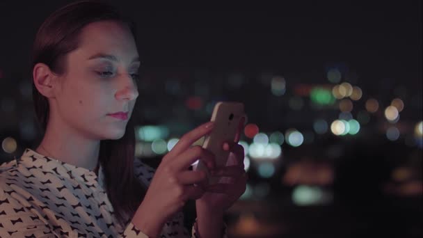 Uma mulher brasileira usando smartphone à noite — Vídeo de Stock