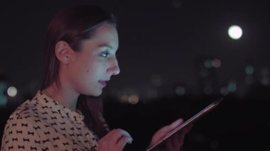 Sao Paulo şehrinde gece tablet kullanan Brezilyalı bir kadın.