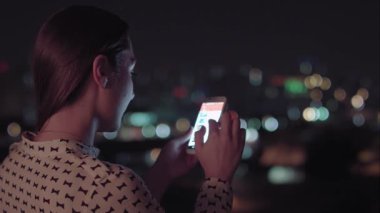 Gece akıllı telefon kullanan Brezilyalı bir kadın.