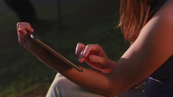 Uma mulher brasileira usando tablet no pôr do sol do parque em So Paulo — Vídeo de Stock
