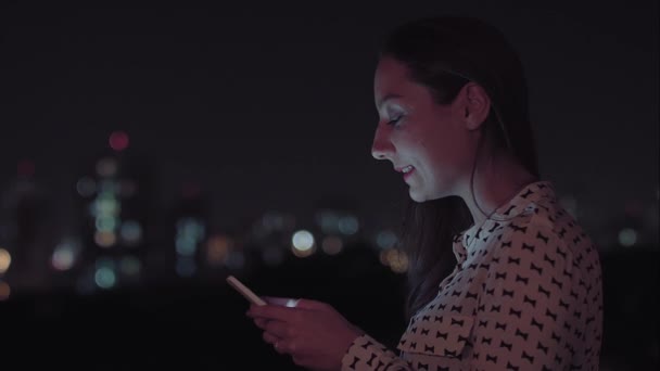 Een Braziliaanse vrouw die 's nachts smartphone gebruikt — Stockvideo