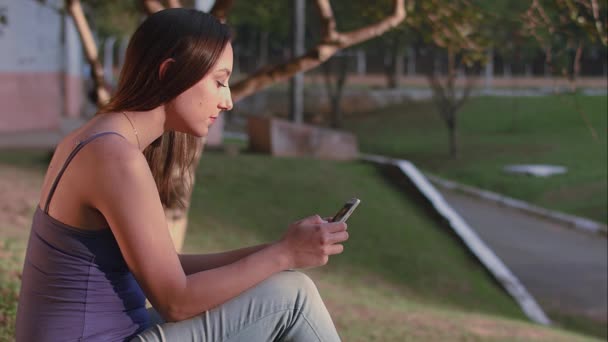 Une femme brésilienne utilisant un smartphone au coucher du soleil du parc à So Paulo — Video