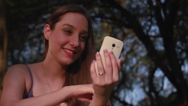 Una mujer brasileña usando smartphone en el atardecer del parque en So Paulo — Vídeo de stock