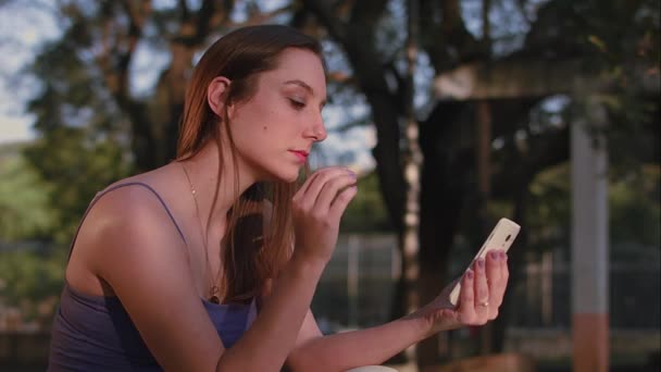 Бразилька, использующая смартфон на закате в парке Со Пауло — стоковое видео