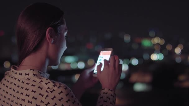 Uma mulher brasileira usando smartphone à noite — Vídeo de Stock