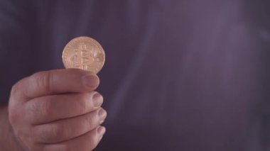 Brezilyalı yaşlı bir kadının eli Bitcoin parasının değerini gösterir