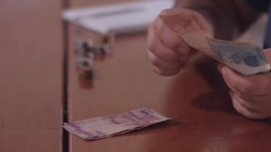 Orta yaşlı Brezilyalı bir adam evin faturalarını ödemek için para sayıyor.