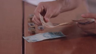 Genç Brezilyalı bir adamın elleri, ayın faturalarını ödemek için parayı sayar.