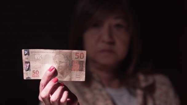 Brazilská dáma ukazuje poznámku 50 reais pro kameru