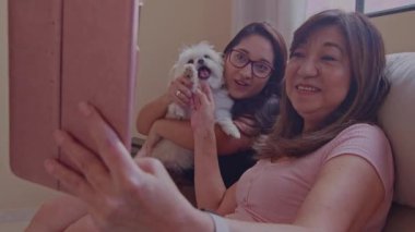 Anne ve kızı tableti kullanarak bir video görüşmesinde sohbet ediyorlar.