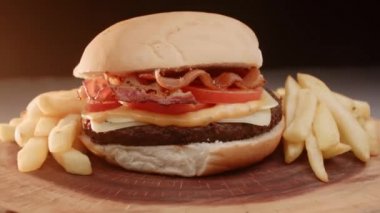 Domatesli hamburger, pastırma, peynir, sos ve patates kızartması.