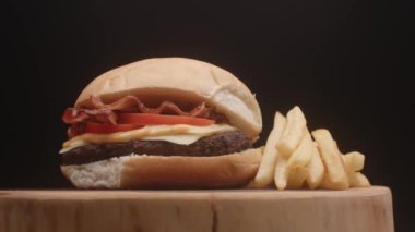 Domatesli hamburger, pastırma, peynir, sos ve patates kızartması.