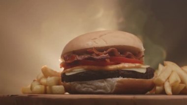 Domatesli hamburger, pastırma, peynir, sos ve patates kızartması.