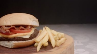 Domatesli hamburger, pastırma, peynir, sos ve patates kızartması.