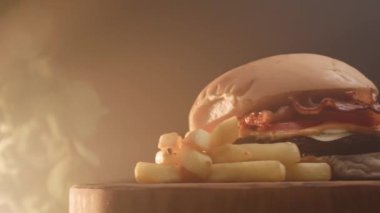 Domatesli hamburger, pastırma, peynir, sos ve patates kızartması.