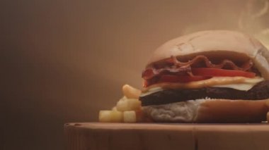 Domatesli hamburger, pastırma, peynir, sos ve patates kızartması.