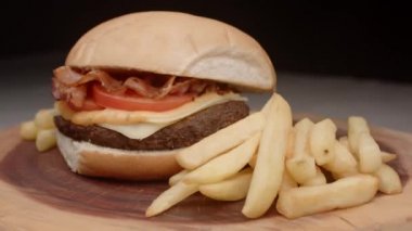 Domatesli hamburger, pastırma, peynir, sos ve patates kızartması.