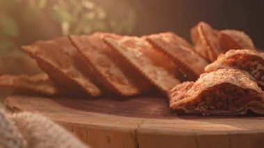 Tahtada birkaç kızarmış hamur işi ve ikiye bölünmüş etli börek.