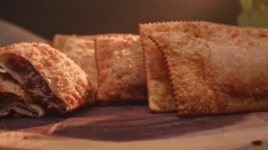 Tahtada birkaç kızarmış hamur işi ve ikiye bölünmüş etli börek.