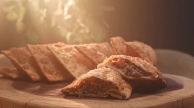 Tahtada birkaç kızarmış hamur işi ve ikiye bölünmüş etli börek.