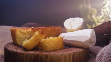 Kesilmiş bir parça Cassava keki ve arka planda manyok.