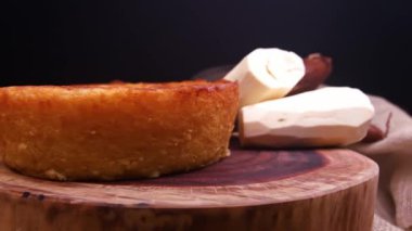 Kesilmiş bir parça Cassava keki ve arka planda manyok.