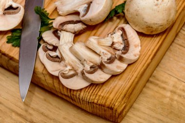 Bir mutfak ahşap tahta üzerinde bıçak yalanlarla mantar dilimlenmiş