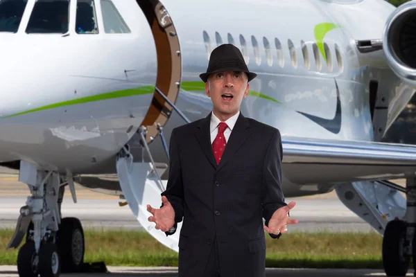 Handsome business man near the steps of a private jet wearing a hat.