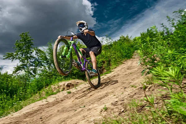 Dağ bisikleti bisikletçi bir mtb bisiklet üzerinde wheelie dublör yapıyor