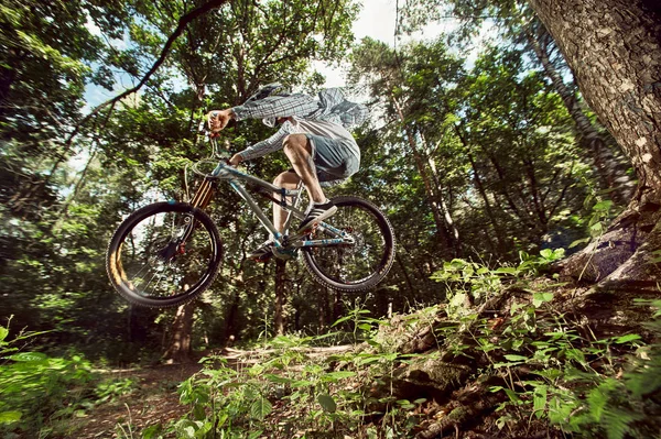 Moscow, Russia - August 18, 2017: Jump and fly on a mountain bike. Rider in action at mountain bike sport. Biker riding in forest. Cool athlete cyclist on a bike. MTB biking. — Stock Photo, Image