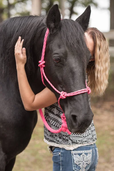 Mujer rubia dando un abrazo a un caballo negro — Foto de Stock