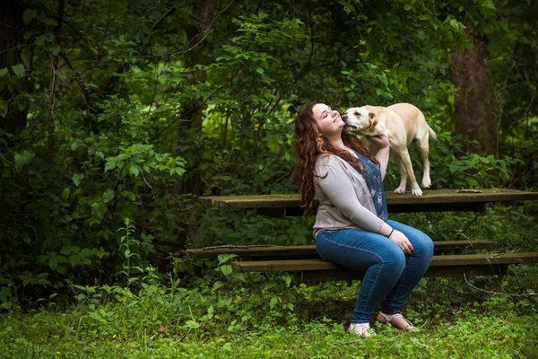 Junge Frau bekommt Aufmerksamkeit von Hund im Park — Stockfoto