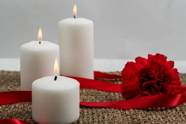 Three candles with ribbon and carnation