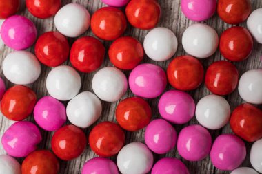 Bir beyaz boyalı tahta üzerine düzenlenmiş kırmızı beyaz ve pembe şeker