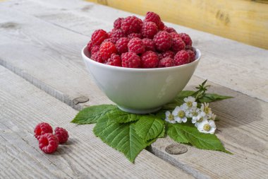 Sulu olgun ahududu, papatya çiçekleri matricaria, mükemmel renkli yaz arka plan ağaç doku ile süslenmiş dolu kase