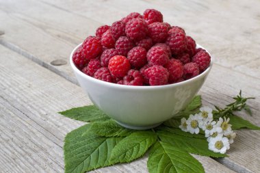 Sulu olgun ahududu, papatya çiçekleri matricaria, mükemmel renkli yaz arka plan ağaç doku ile süslenmiş dolu kase