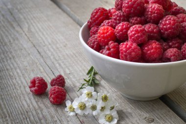 Sulu olgun ahududu, papatya çiçekleri matricaria, mükemmel renkli yaz arka plan ağaç doku ile süslenmiş dolu kase