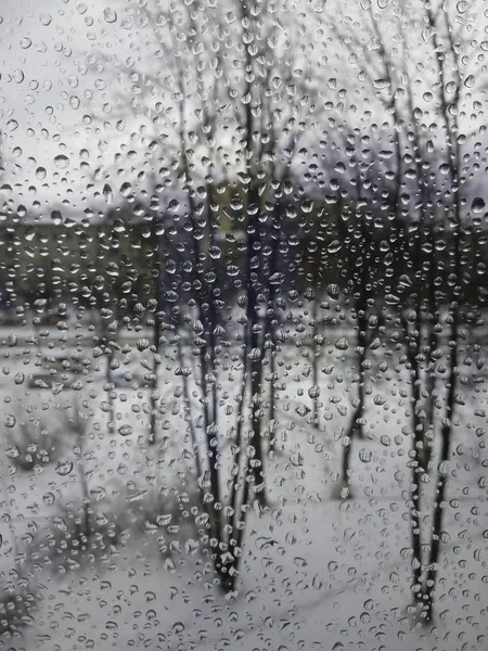 Regendruppels op het glas, regen in het nieuwe jaar, regen met sneeuw, nat weer, regenachtig weer, depressie, grijze lucht — Stockfoto
