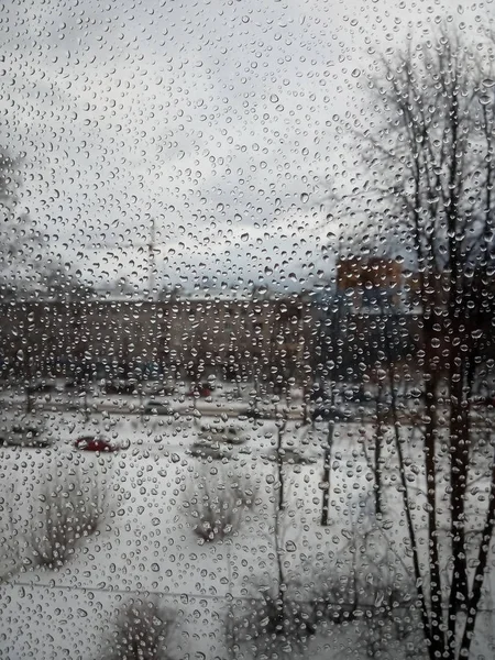 Gotas de lluvia en el vidrio, lluvia en el nuevo año, lluvia con nieve, clima húmedo, clima lluvioso, depresión, cielo gris — Foto de Stock