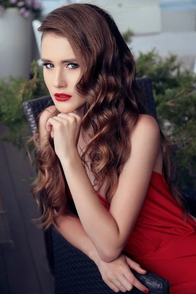 Gorgeous woman with dark curly hair in luxurious red dress — Stock Photo, Image