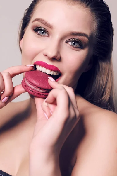 Bela jovem mulher com cabelo escuro comer macaroon doce — Fotografia de Stock