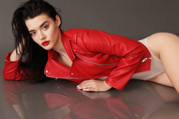 Schönes junges Mädchen mit dunklen Haaren und glühender Haut in rotem Leder — Stockfoto