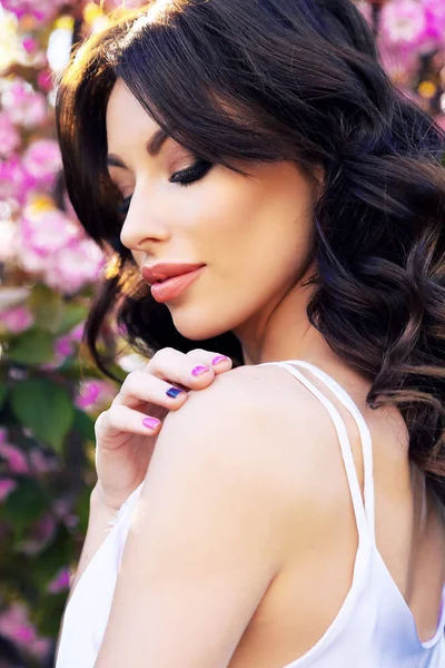 Schönes Mädchen im eleganten Outfit posiert im Frühlingsblütengarten — Stockfoto