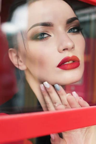 Menina bonita com cabelo escuro e maquiagem lábios vermelhos, posando em vermelho — Fotografia de Stock